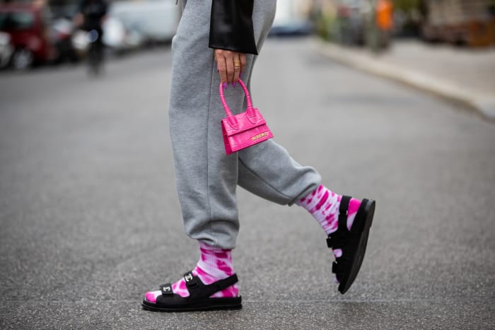 woman-wearing-grey-sweatpants-with-tie-dye-socks-chanel-sandals-pink-mini-jacquemus-bag
